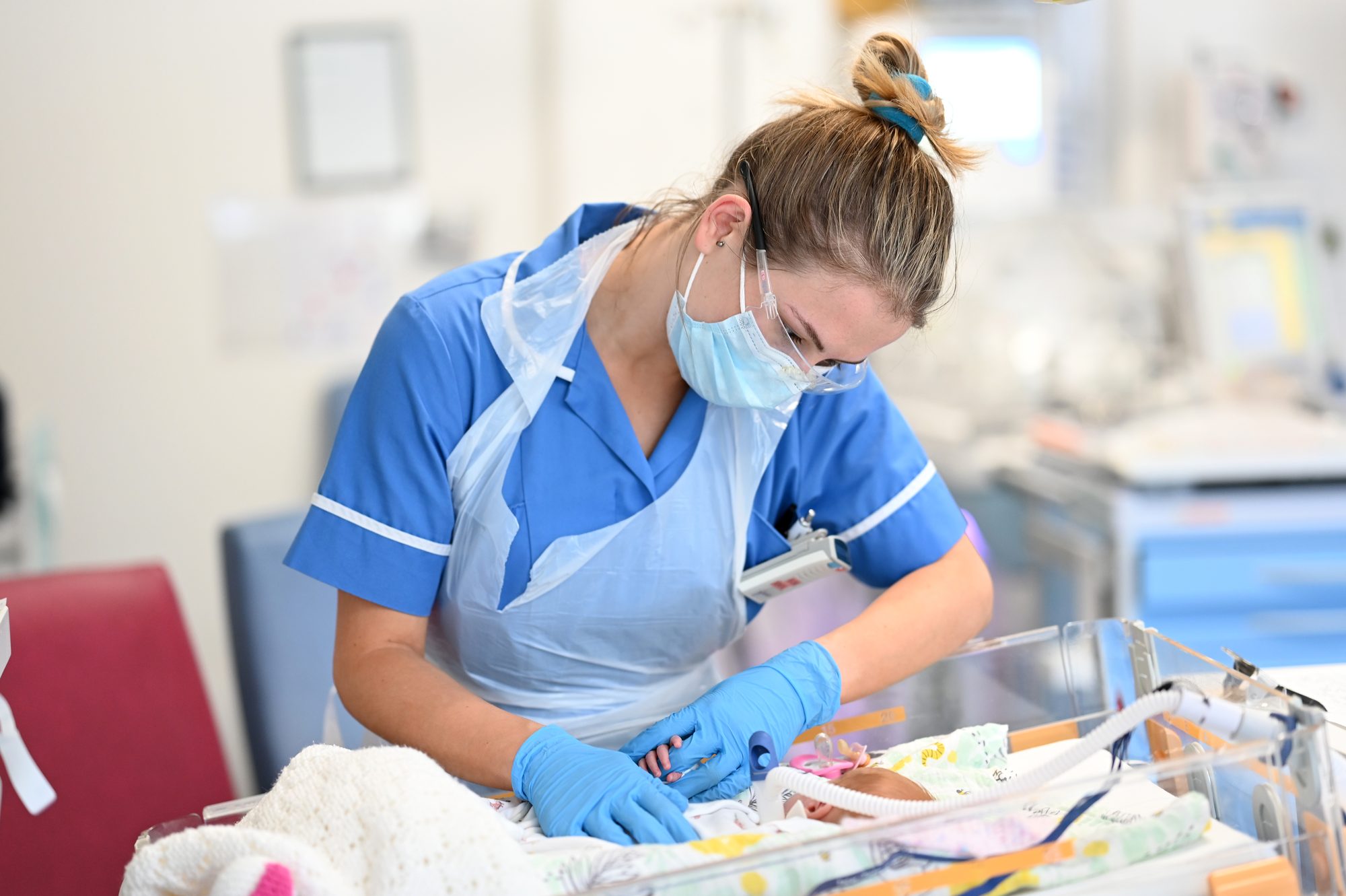 A neonatal nurse caring for a baby in an incubator